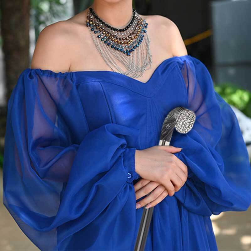 a woman in a dark blue dress holding a black stick with a diamante-studded handle