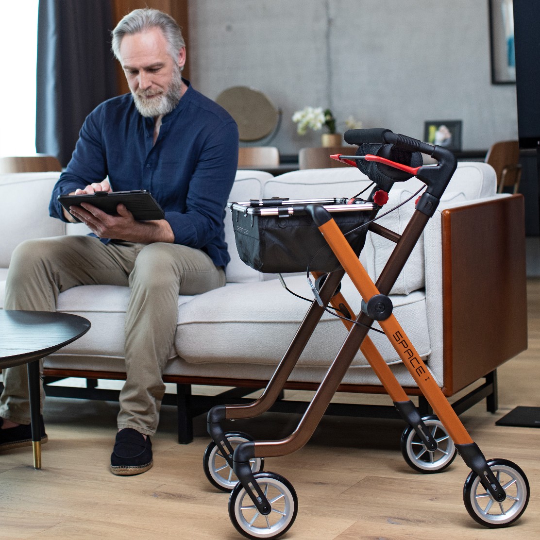 Elderly man sitting with the Rehasense Space I Lightweight Indoor Rollator (Toffee and Brown)