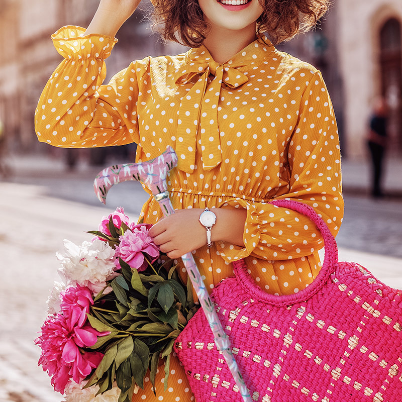 woman in a yellow top holding a pink, dragonfly-print stick